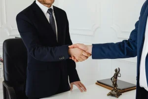 Apretón de manos en un despacho con estatua de la justicia – Alquiler con opción a compra en Cataluña