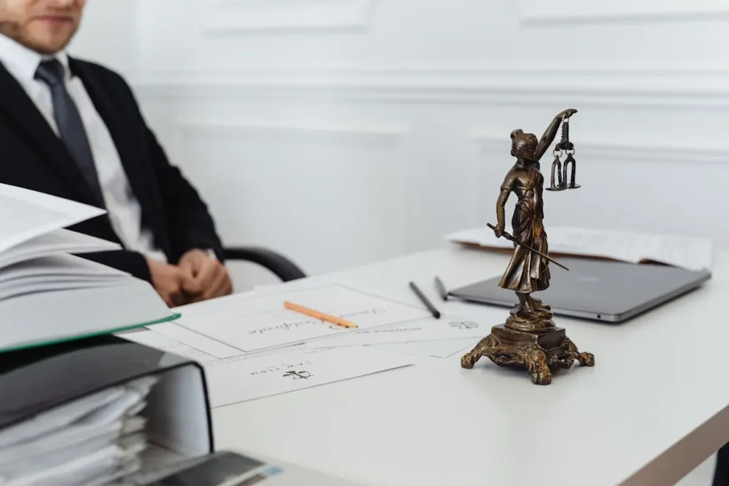 Mesa de despacho jurídico con documentos y estatua de la justicia – Capitulaciones matrimoniales en Cataluña