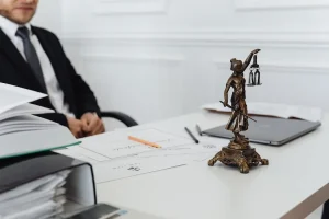 Mesa de despacho jurídico con documentos y estatua de la justicia – Capitulaciones matrimoniales en Cataluña