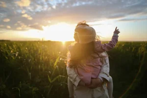Padre con su hija en brazos en un campo al atardecer – El reconocimiento de hijo ante notario